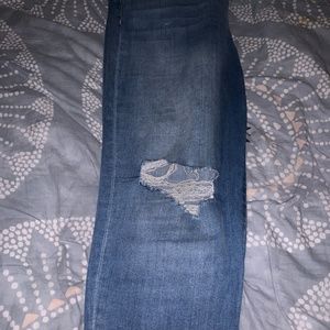 Denim jeans with hole in knee and frayed ankle